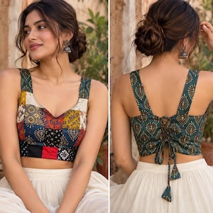 May include: A sleeveless crop top featuring a patchwork front with various colorful patterns and a solid dark green back with a repeating teardrop motif. The back includes a lace-up closure with fabric ties and dangling tassels at the ends.
