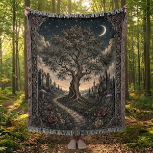 Puede incluir: Una manta tejida rectangular que presenta un gran árbol central, un camino de piedra y la silueta de un castillo bajo una luna creciente y un cielo estrellado. La manta tiene un borde floral decorativo y flecos en los extremos.