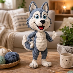 May include: A crocheted stuffed animal shaped like a wolf with dark blue and cream yarn. The figure has large blue eyes, a black nose, an open mouth with a red tongue, and a bushy tail. It stands upright with one arm raised in a thumbs-up gesture.