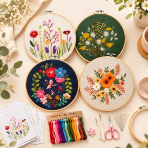 May include: Four circular embroidery hoops featuring floral designs on white, dark green, navy blue, and light gray fabric. Included are colorful embroidery floss skeins, a seam ripper, scissors, needles, and printed pattern instruction cards.
