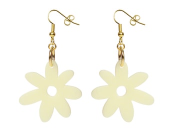 May include: A pair of gold dangle earrings with a cream-colored flower charm. The flower has a hole in the center.