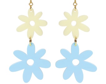 May include: A pair of dangle earrings featuring two layered flower charms. The top flower is cream colored and the bottom flower is light blue.