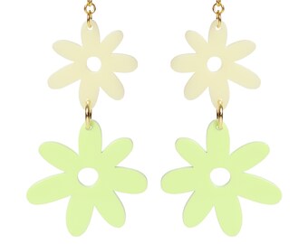 May include: A pair of gold dangle earrings with two layered flower charms. The top flower is cream colored and the bottom flower is light green.