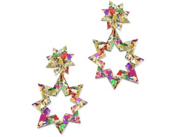 May include: A pair of gold star-shaped earrings with a confetti-like pattern in shades of pink, red, green, blue, and yellow.