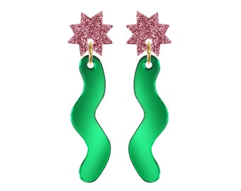May include: A pair of green and pink dangle earrings. The earrings feature a wavy green shape with a pink glitter star charm at the top.