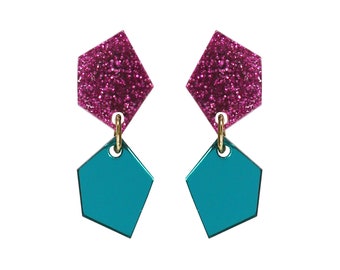 May include: A pair of dangle earrings with a pink glitter top and a teal bottom. The earrings are shaped like a pentagon.