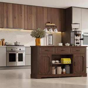 May include: A dark wood kitchen island featuring three top drawers with black handles, two side cabinets with paneled doors, and an open center shelf containing white mugs, yellow packages, and various storage canisters for kitchen organization.
