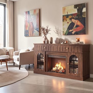 May include: A dark wood fireplace console featuring a central electric fire insert with glowing flames, flanked by two glass-paneled cabinets with arched tops. The unit includes a top drawer with vertical grooved detailing and small gold knobs.