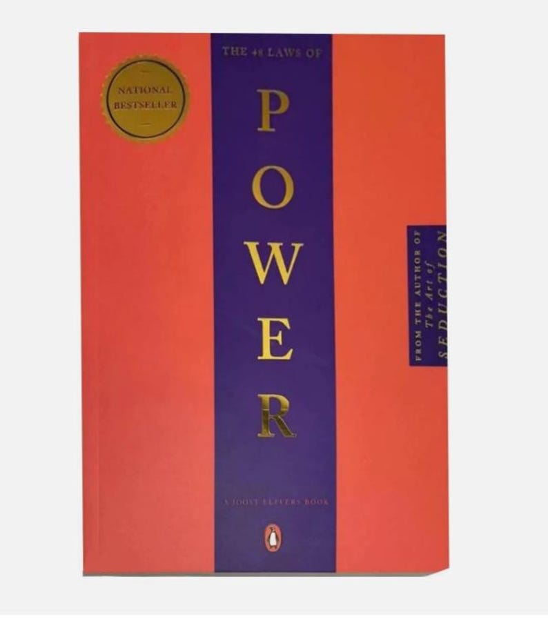 May include: A book titled The 48 Laws of Power with a bright orange cover and a central vertical purple stripe. The title is printed in gold lettering. A gold circular National Bestseller seal is in the top left corner, and a small penguin logo is at the bottom.