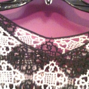 May include: Black and white lace fabric with a delicate floral pattern. The lace is soft and flowing, and it would be perfect for a variety of projects, such as clothing, accessories, or home decor.