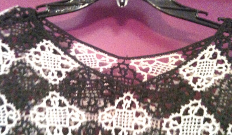 May include: Black and white lace fabric with a delicate floral pattern. The lace is soft and flowing, and it would be perfect for a variety of projects, such as clothing, accessories, or home decor.