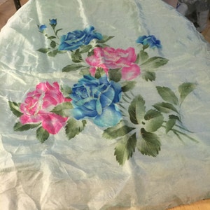 May include: A light blue fabric with a floral design featuring pink and blue roses with green leaves.