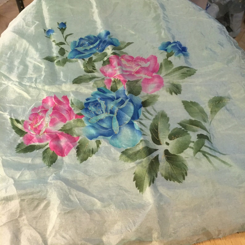 May include: A light blue fabric with a floral design featuring pink and blue roses with green leaves.