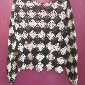 May include: Black and white crochet top with a scalloped hem and long sleeves.