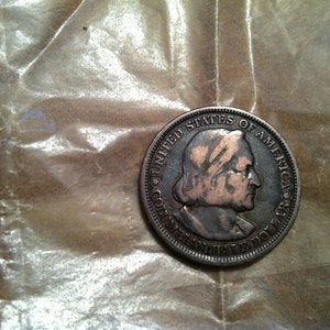 May include: A copper-colored half dollar coin with the inscription "United States of America" and "Half Dollar" around the edge. The coin features a profile of a person with a long, flowing hairstyle.