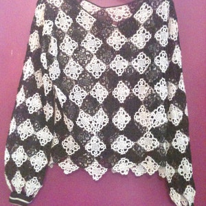 May include: Black and white crochet top with a scalloped hem and long sleeves. The sleeves have a black and white striped cuff.