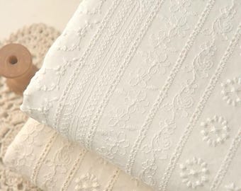 May include: Two folded pieces of white fabric featuring intricate vertical embroidery patterns. The textile displays repeating floral motifs, delicate scalloped lines, and geometric stitching arranged in parallel columns across the surface.