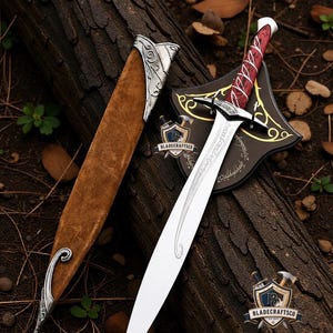 May include: A silver-toned sword with a red wood-grain handle and intricate metal crossguard, accompanied by a brown suede scabbard featuring ornate silver metal accents. A black display plaque with gold filigree and elvish script is positioned behind.