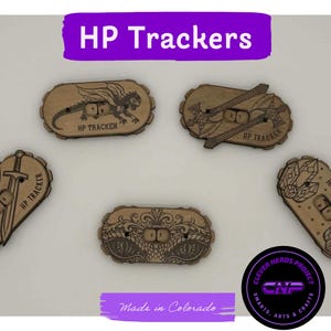 May include: Five oval-shaped wooden HP Trackers with engraved designs including a dragon, crossed swords, a single sword, ornate patterns, and crystals. Each tracker features a central slot with rotating number dials and the text HP TRACKER.