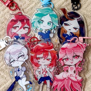Könnte beinhalten: Sechs Acryl-Schlüsselanhänger mit stilisierten Anime-Figuren mit leuchtenden Haarfarben wie Rot, Minzgrün, Dunkelbraun, Weiß und Pink. Jeder Anhänger ist an einem passenden oder kontrastierenden Kunststoff- oder Metallverschluss befestigt.
