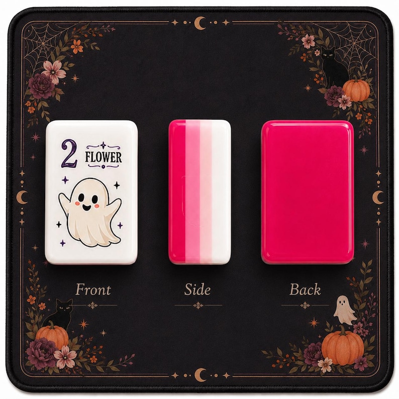 May include: Three rectangular mahjong tiles displayed on a black mat with floral and ghost motifs. The left tile is white with a ghost illustration and the text 2 FLOWER. The middle tile shows pink and white stripes. The right tile is solid pink.