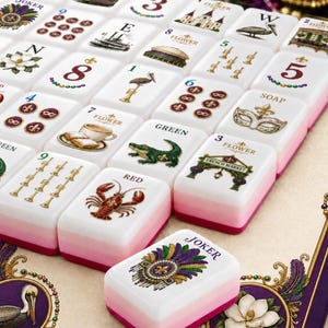 May include: A set of white Mahjong tiles with pink and red bases, featuring colorful illustrations of New Orleans themes including a lobster, pelican, alligator, French Market, and masks. Each tile displays specific numbers, letters, or the word Joker.