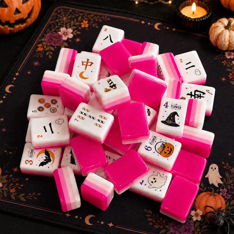 May include: A collection of rectangular Mahjong tiles featuring a pink and white gradient design. Several tiles display Halloween-themed graphics including ghosts, pumpkins, witch hats, and bats, alongside traditional numerical and character symbols.