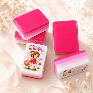 May include: A set of rectangular soap bars with a layered pink and white design. One bar features a cartoon illustration of a fairy with a strawberry dress and the text JOKER. Another bar shows a rabbit illustration with the text SOAP.
