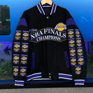 May include: A black varsity jacket with purple accents, featuring the Los Angeles Lakers logo and the text 17-Time NBA FINALS CHAMPIONS. Both sleeves are decorated with multiple embroidered patches commemorating championship years from 1949 to 2020.