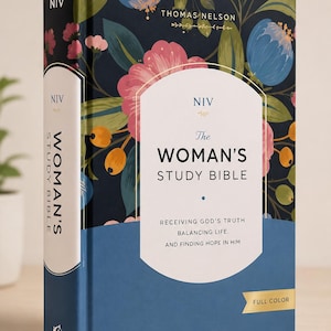 Może przedstawiać: Biblia do studiowania NIV dla kobiet w twardej oprawie z ciemnogranatową okładką ozdobioną kolorowym wzorem kwiatowym w odcieniach różu, błękitu i pomarańczy. Z przodu znajduje się biały panel z tytułem oraz tekstem Receiving God's Truth, Balancing Life, and Finding Hope in Him.