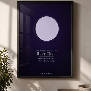 Könnte beinhalten: Ein gerahmtes vertikales Poster mit einem dunkelblauen Nachthimmel und einem großen, hellen, kreisförmigen Mond. Der Text lautet: THE NIGHT YOU ARRIVED, Baby Theo, AUCKLAND, NZ, November 4, 2025, und NEW BABY. Der Druck befindet sich in einem schwarzen Rahmen.