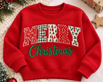 May include: A bright red long-sleeve sweatshirt featuring the word MERRY in large, multi-patterned block letters with various holiday prints, and the word Christmas embroidered in green cursive script across the center of the chest.