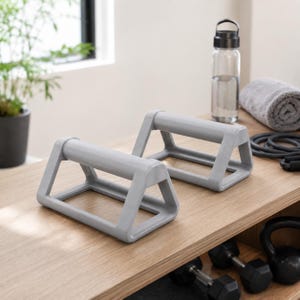 May include: A pair of light gray push-up bars with a sturdy, angular frame design. These fitness tools feature a wide base for stability and a horizontal grip handle, constructed from a smooth, solid material for consistent support during exercise.