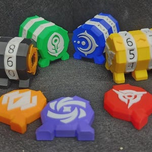 May include: A collection of four cylindrical combination lock boxes in black, green, blue, and yellow, each featuring rotating number dials. Accompanying these are three flat, shaped tokens in orange, purple, and red, each displaying a white graphic symbol.