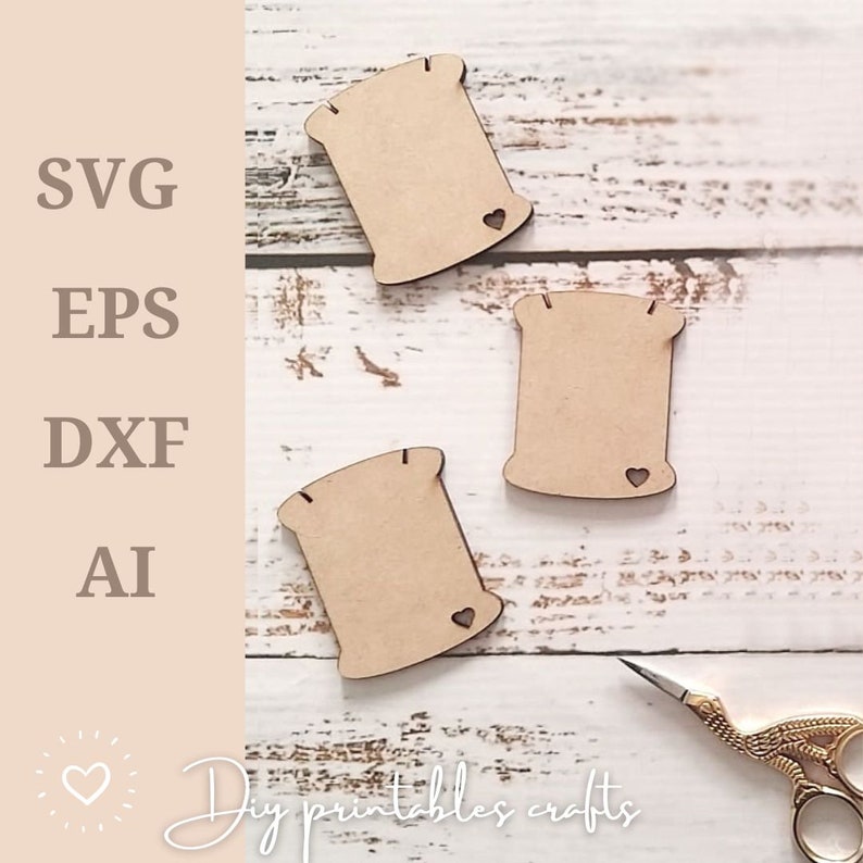 May include: Three unfinished wooden spool shapes with a small heart cutout on each. The spools are on a white wooden surface with a pair of gold scissors.