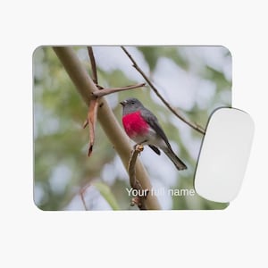 May include: A rectangular mouse pad featuring a photographic print of a small bird with a dark grey head and a vibrant pink chest perched on a thin branch. The text "Your full name" is printed in white at the bottom centre of the mouse pad.