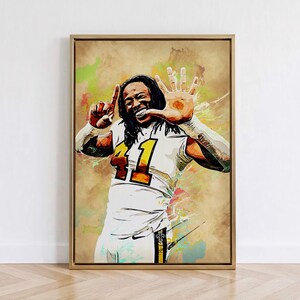 May include: A framed wall art print featuring a watercolor-style illustration of a football player with long dark hair wearing a white jersey with the number 41 in gold and black. The player is smiling and holding up one finger on one hand and five fingers on the other.