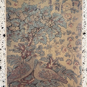 May include: Vintage paper with a detailed illustration of two birds perched amidst a floral and tree design. The artwork features a color palette of beige, blue, and burgundy, with visible text fragments. The paper has a distressed, aged appearance.