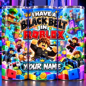 Puede incluir: Un vaso cilíndrico con un estampado gráfico multicolor vibrante que muestra personajes en bloques, un castillo y el texto I HAVE A BLACK BELT IN ROBLOX y YOUR NAME. El diseño incluye una pajita transparente y una tapa.