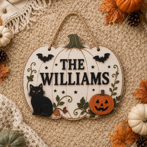 以下が含まれることがあります： THE WILLIAMSという黒い文字、黒猫、ジャック・オー・ランタン、2匹の黒いコウモリ、緑の蔓の装飾が施された、カボチャの形をした白い木製の壁掛け看板。上部には壁掛け用のジュートロープが付いています。