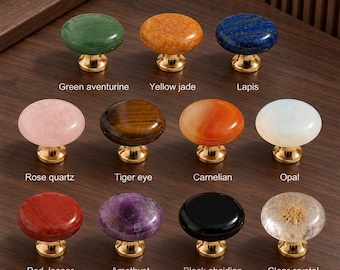 May include: A collection of eleven round cabinet knobs with gold-toned metal bases. The knobs feature various stones including green aventurine, yellow jade, lapis, rose quartz, tiger eye, carnelian, opal, red jasper, amethyst, black obsidian, and clear crystal.