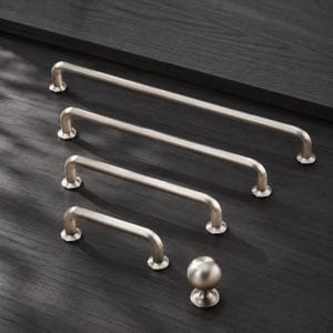 May include: A collection of four brushed nickel cabinet pulls of varying lengths and one matching round cabinet knob. Each pull features a smooth, cylindrical bar design with two circular mounting posts, while the knob has a spherical shape.