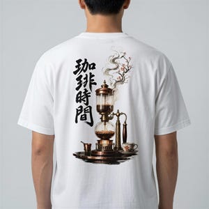 May include: A white t-shirt featuring a back graphic of a copper-toned glass siphon coffee maker with rising steam and cherry blossom branches. Black Japanese kanji characters are printed vertically to the left of the coffee brewing apparatus.