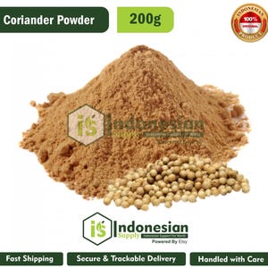 Könnte beinhalten: Ein Haufen hellbraunes Korianderpulver mit einer kleinen Ansammlung ganzer, runder, beigefarbener Koriandersamen davor. Der Text "Coriander Powder" und "200g" erscheint oben, mit einem runden "100% Original Product" Abzeichen in der Ecke.