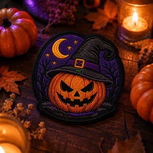 May include: A circular embroidered patch featuring an orange jack-o'-lantern wearing a black witch hat with a purple band and gold buckle. The background is a dark purple night sky with a yellow crescent moon, stars, and black tree silhouettes.