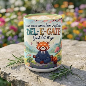 May include: A ceramic mug featuring a red panda in a blue suit meditating on a rock. The text reads: Inner peace comes from 3 syllables: DEL-E-GATE Just let it go. The design includes a landscape with trees, flowers, and a lake, with a light green rim.