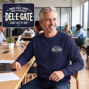 May include: A navy blue crewneck sweatshirt featuring a white graphic on the chest that reads: INNER PEACE COMES FROM 3 SYLLABLES DEL-E-GATE JUST LET IT GO! The design includes decorative star and flourish accents surrounding the text.