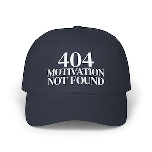 May include: A navy blue baseball cap featuring white embroidered text on the front that reads 404 MOTIVATION NOT FOUND. The cap has a structured crown, a curved brim, and a button at the top center, presenting a clean and simple design.