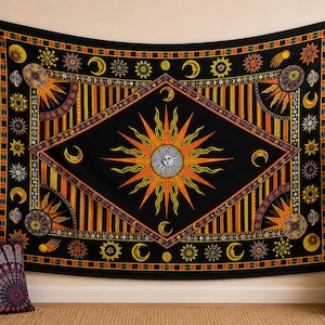 May include: A rectangular wall tapestry featuring a central sun with a human face surrounded by orange and yellow rays inside a diamond shape. The black background is decorated with celestial motifs including moons, stars, and planets in gold.