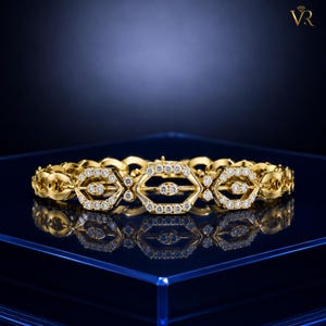 May include: A gold link bracelet featuring a series of repeating hexagonal motifs. Each hexagon is outlined with small, clear, round-cut stones, and a central horizontal bar within each hexagon is also set with small, clear, round-cut stones.